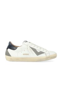 Baskets en cuir blanc avec des accents gris et noirs, présentant un panneau en suède texturé et une pointe arrondie. Comprend des lacets plats et un détail logo.