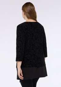 Mustat samettitunika, jossa on kukkakuosi, kolmannes hihoista ja kerroksellinen helma, joka on sileä tekstuuriltaan ja rento istuvuudeltaan.