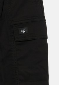 Fekete cargo sort oldalzsebbel és Calvin Klein logó fPatch-el. Tartós anyagból készült, látható varrási részletekkel.