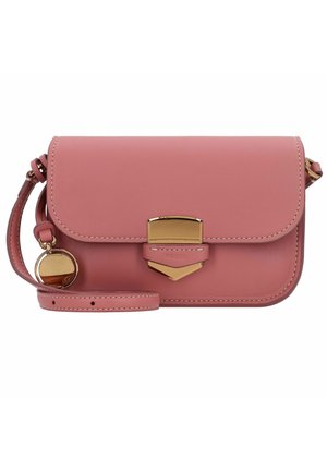 Sac bandoulière en cuir rose avec fermeture dorée et breloque ronde dorée suspendue à la sangle réglable sur fond blanc.