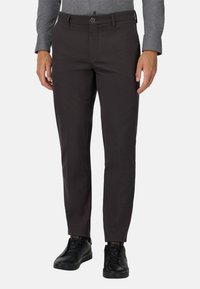 Ciemnoszare spodnie wykonane z gładkiego materiału, o prostym kroju, z p�ętelkami na pasek i zapięciem na guzik, w połączeniu z czarnymi trampkami.