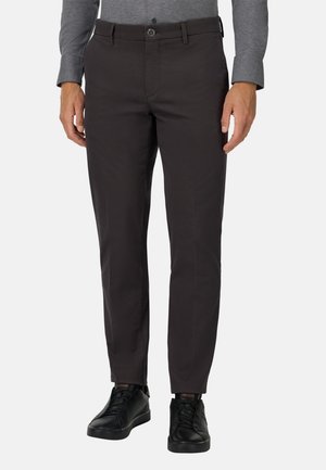 Un pantalon gris foncé en tissu lisse, avec une coupe droite, des passants de ceinture et une fermeture à bouton, associé à des baskets noires.