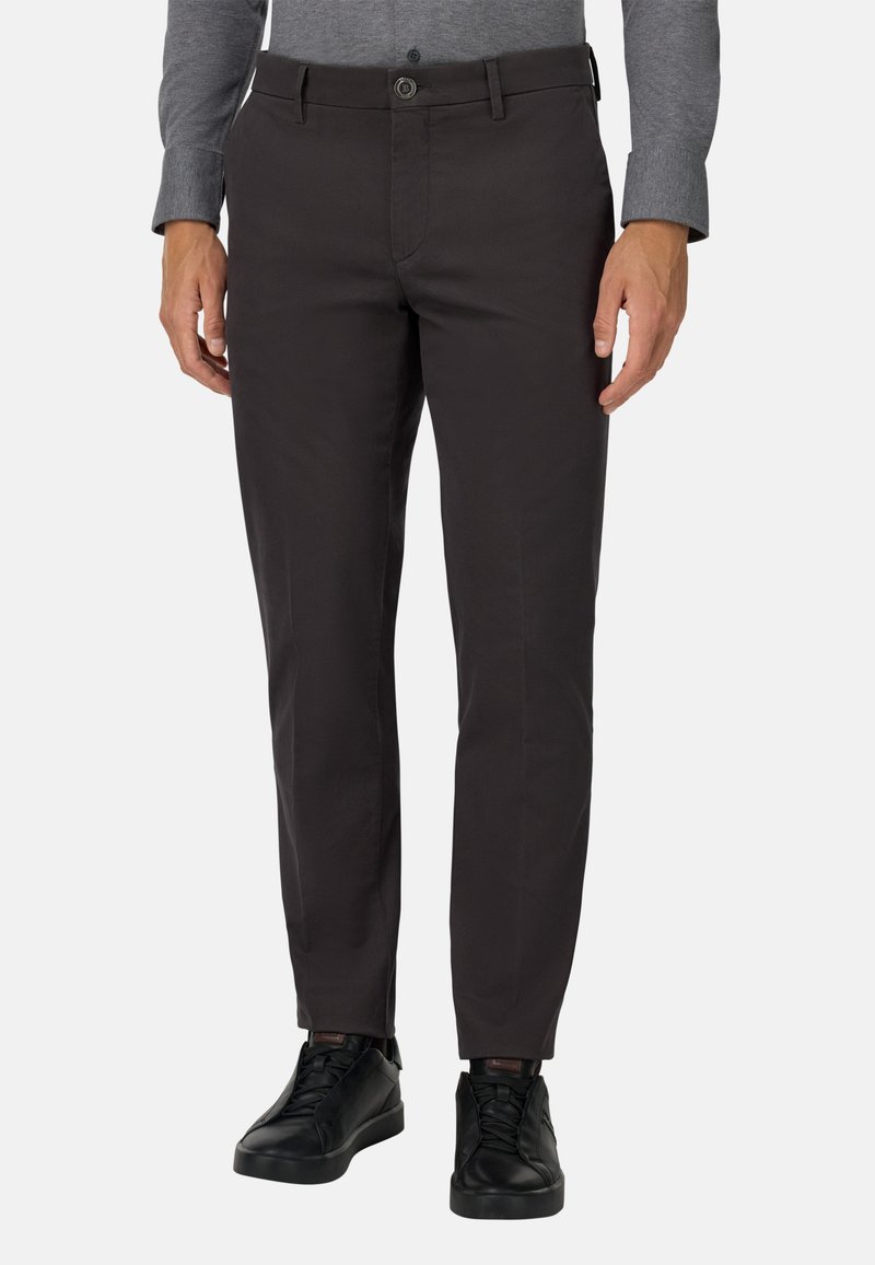 Ciemnoszare spodnie wykonane z gładkiego materiału, o prostym kroju, z pętelkami na pasek i zapięciem na guzik, w połączeniu z czarnymi trampkami.