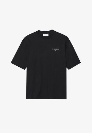 Mustjas puuvillane T-särk lühikeste varrukatega ja ümmarguse kaelusega. Vasakul rinnal on valge teksti print: "VIS TES RÊVES LA TOUR EIFFEL PARIS."