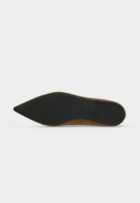 Semelle d'une chaussure marron à bout pointu avec une semelle noire lisse et un patch rectangulaire en caoutchouc au talon sur fond blanc.