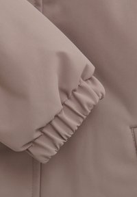 Rosa syntetisk jacka med manschett och elastisk samling, som har en slät yta och en minimalistisk design. Sömmen är synlig vid kanten.