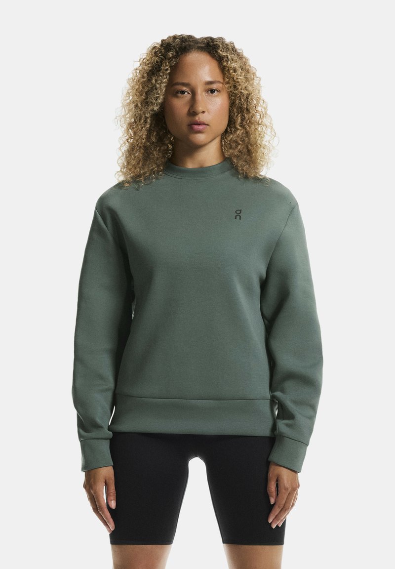 Green sweatshirt with a high neck, ribbed cuffs, and waistband. Features a small black logo on the upper left chest. Textured fabric.