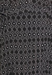 Czarna tkanina z białym geometrycznym wzorem diamentów, z małymi centralnymi kwadratami i powtarzającym się tekstem "NIKKIE" wzdłuż krawędzi diamentów.