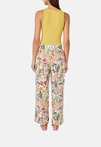 Top de tirantes amarillo con canalé y pantalones holgados con un estampado tropical multicolor. La tela parece ligera y tiene una textura suave.
