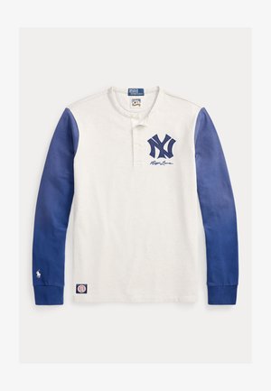 Άσπρη μπλούζα Henley με μακριά μανίκια, μπλε μανίκια, λογότυπο "NY" σε ναυτικό μπλε και σήμανση Polo Ralph Lauren στο στήθος και τα μανίκια.