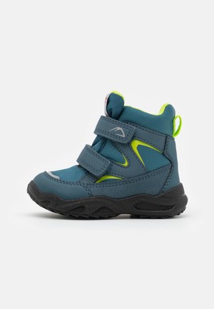 Botte bébé bleue et verte avec semelle noire, deux sangles réglables en velcro, cheville rembourrée et languette à l’arrière.