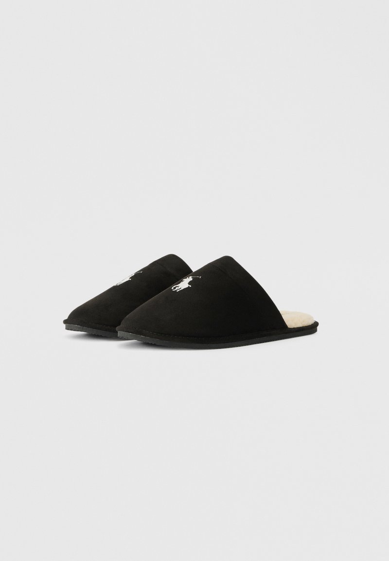 Schwarze Slipper zum Hineinschlüpfen mit weißem gesticktem Pferdelogo und crèmefarbener, plüschiger Fütterung, auf einem schlichten, hellen Hintergrund.