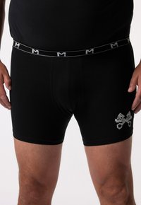 Černé bavlněné boxerky s upevněným střihem, které mají pas se logem a grafický potisk zkřížených pístů na levé noze.