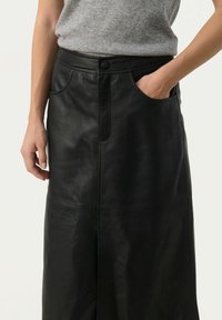Black leather skirt with a high waist, front pockets, and visible stitching details. Smooth texture with a slightly glossy finish.