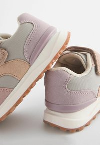 Chaussures de sport légères avec un mélange de matériaux texturés gris et rose, dotées d'une semelle à motif et d'une sangle velcro ajustable.