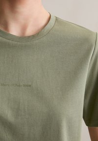 T-shirt vert olive en tissu doux, avec un col rond et des manches courtes. "Marc O'Polo DENIM" imprimé dans une teinte plus sombre.