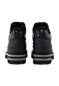 Een paar zwarte leren laarzen met een voering van bont, dikke gestreepte zolen en "BOGNER" gegraveerd aan de achterkant, gezien vanaf de achterkant.