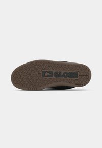 Σόλα παπουτσιού με καφέ σχέδιο πέλματος και το λογότυπο "GLOBE" ανάγλυφο στο κέντρο, σε λευκό φόντο.
