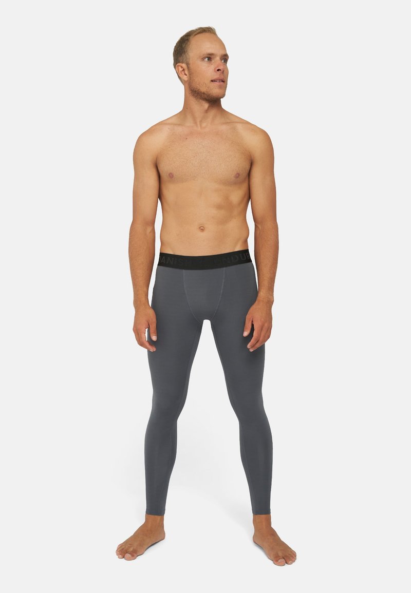 Mallas grises ajustadas para hombre con una cinturilla elástica negra con marca, textura suave y diseño de longitud completa.
