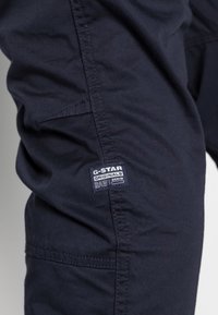 Ciemnogranatowe spodnie cargo z bawełny, z przeszywanym szwem, boczną kieszenią oraz charakterystyczną metką z napisem "G-Star RAW".