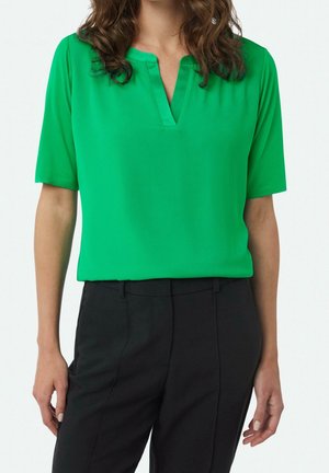 Chemise verte à manches courtes avec col en V ; fabriquée en tissu lisse, présentant une coupe décontractée et une couleur unie sans motifs.