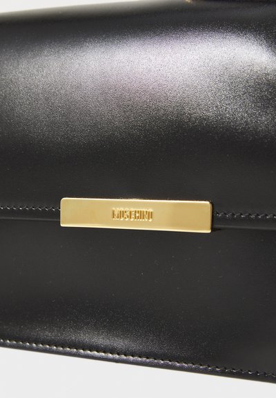 Juodas odinis pašto krepšys su lygiu paviršiumi, auksinėmis detalėmis su "Moschino" ženklu ir glotnia, minimalistine dizaino estetika.