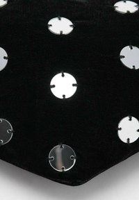 Tessuto nero con borchie di metallo rotonde e argento, distribuite uniformemente e fissate da quattro rebbi su ogni borchia.