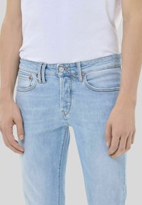 Jeans in denim azzurro chiaro con una vestibilità slim, design a cinque tasche e cuciture a contrasto. Include una chiusura con bottone metallico e passanti per cintura.