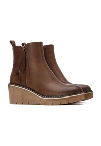 Botas de tobillo con cuña de cuero marrón con cremallera lateral, acabado texturizado y costuras blancas contrastantes en la suela. Base de plataforma estable.