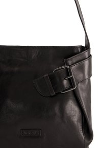 Zwarte leren tas met een gladde textuur, voorzien van een ronde gesp-accent en een subtiel logo-label aan de onderkant. Verstelbare schouderriem.