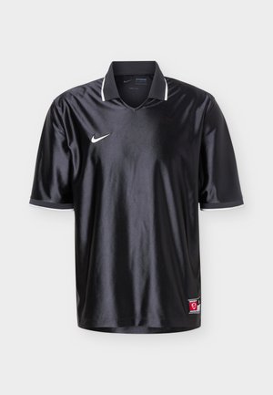 Czarny sportowy trykot Nike z krótkimi rękawami, białym obszyciem kołnierza, białym logo Swoosh na piersi oraz małą czerwoną metką przy dolnym brzegu.