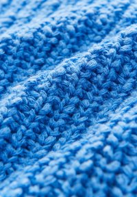 Tessuto lavorato a maglia blu con un motivo testurizzato caratterizzato da punti distintivi e tonalità variabili, creando profondità e morbidezza.