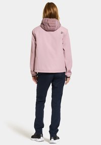 Ljusrosa vattentät jacka med en vadderad huva, kombinerad med marinblå byxor och svarta sneakers. Har en minimalistisk design och elastiska ärmslut.