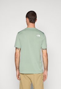 Camiseta de manga corta, color verde claro, con cuello redondo y logo en la parte superior de la espalda. Fabricada con una tela suave y transpirable.