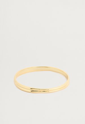 Brazalete de metal dorado con un acabado suave y pulido. Presenta un diseño simple y delgado con dos formas circulares superpuestas.