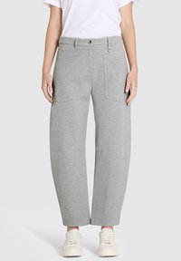 Gray sweatpants with a relaxed fit, side pockets, and a smooth texture. The waistband features a button closure, paired with white sneakers.