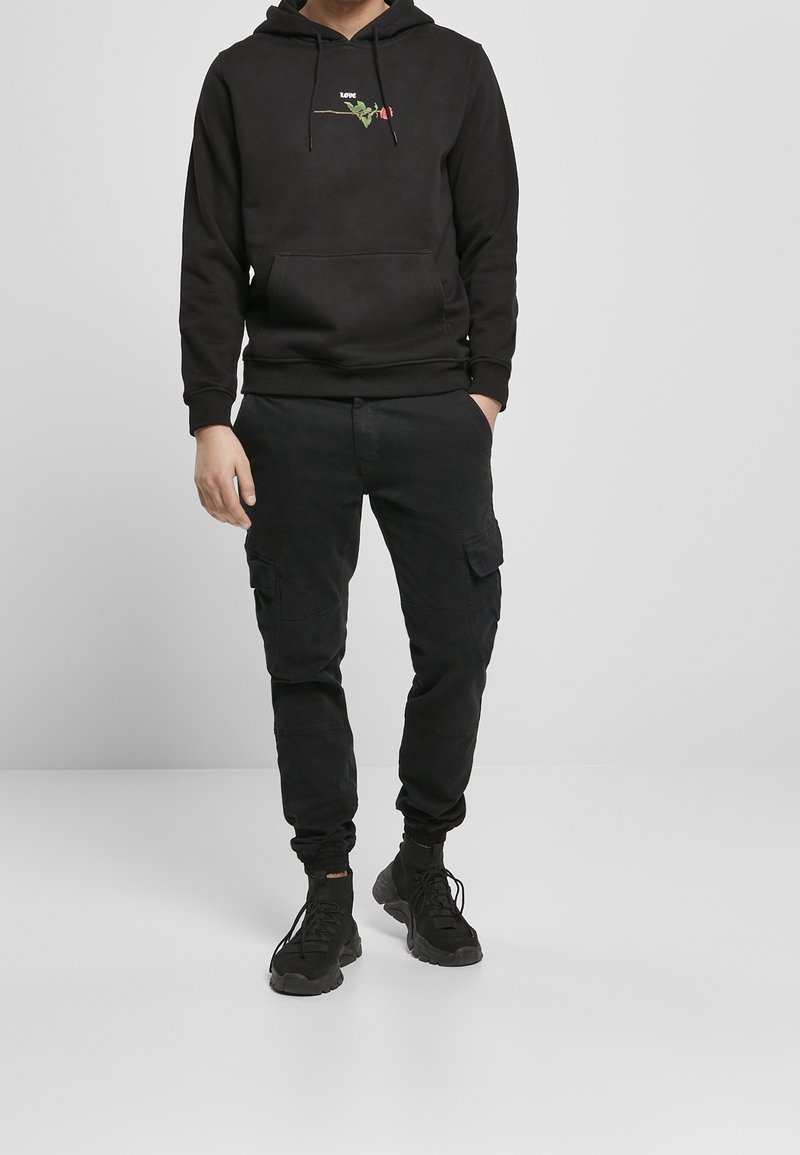Felpa nera con cappuccio, con ricami di una rosa e la scritta "love", abbinata a pantaloni cargo neri e sneakers nere, con una vestibilità comoda.