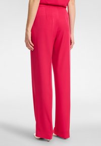 Pantaloni a gamba larga rosa con una trama liscia e vita alta, caratterizzati da pince laterali e una silhouette fluida.