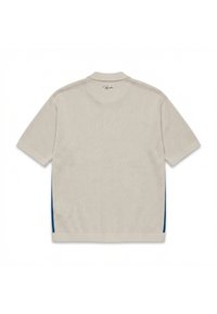 Polo tricoté beige à manches courtes avec des accents bleus sur les côtés et un petit logo en script sous le col à l'arrière.