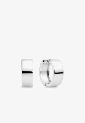 Par af polerede sølv hoop-øreringe, den ene vist lukket og den anden åben, mod en hvid baggrund.