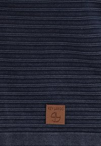 Marineblaue gestreifte Stoff mit strukturiertem Strick. Mit einem braunen Lederetikett, auf dem "Key Largo" embossed ist.
