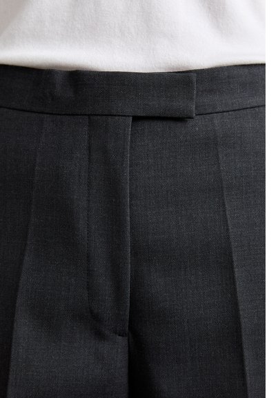 Tumedhallid kohandatud püksid, millel on lapik esiosak, voldid ja sile tekstuur. Includes simple waistline without visible hardware.