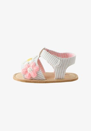 Sandale bébé rayée blanche et beige avec des fleurs brodées roses et blanches et une bride velcro à la cheville.