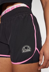 Shorts de sport noirs avec des accents et des coutures roses. Comprend une ceinture élastique et un petit logo blanc sur le bas côté.