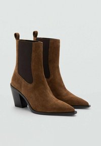 Botine maro din piele întoarsă, cu vârf ascuțit, paneluri elastice pe lateral și toc gros negru. Material texturat cu un finisaj neted.