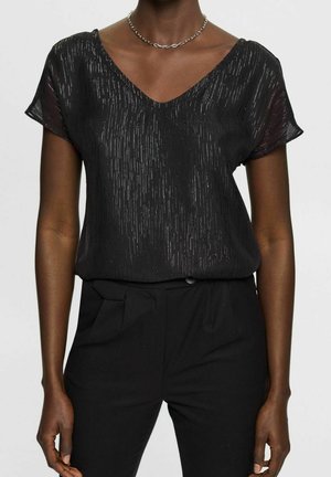 Black V-neck blouse with short sleeves, featuring a textured, shimmering pattern. Paired with black trousers, creating a sleek, understated look.