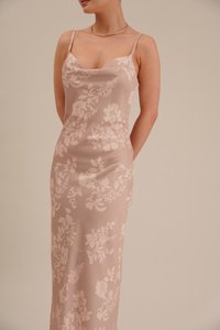 Um vestido de cetim rosa com estampado floral, com alças finas, apresentando uma textura suave e um padrão floral elegante por toda a parte.
