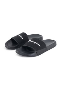 Black slide sandals with mesh fabric strap featuring white "Champion" logo, textured footbed, and flat rubber sole.