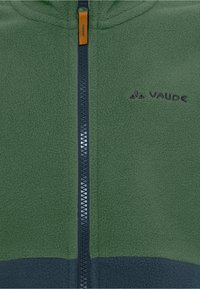 Grön fleecejacka med en marinblå dragkedja och orange draflik. Har en mörkgrå bottensektion och broderad logotyp på vänster bröst.