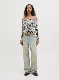 Top a spalle scoperte con un motivo a pois bianco e nero, abbinato a jeans a gamba larga blu chiaro e una cintura marrone. Tessuto testurizzato e vestibilità casual.